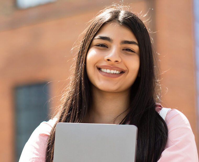 confident college student holding a laptop showing how mental health tips can be helpful for college students.