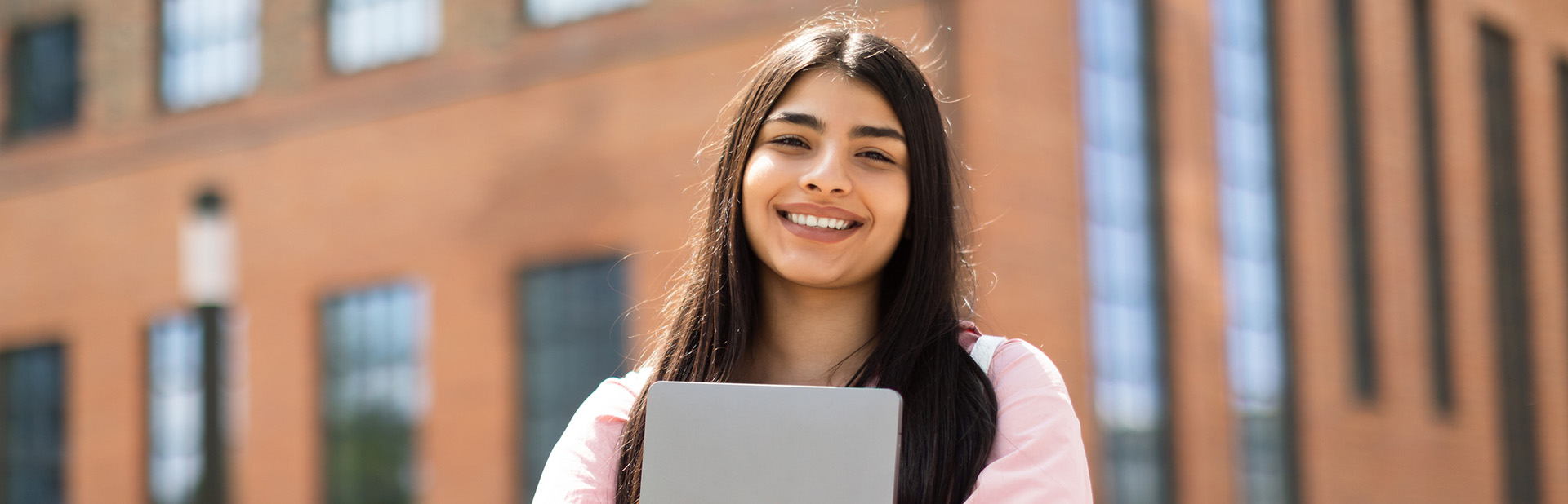 confident college student holding a laptop showing how mental health tips can be helpful for college students.
